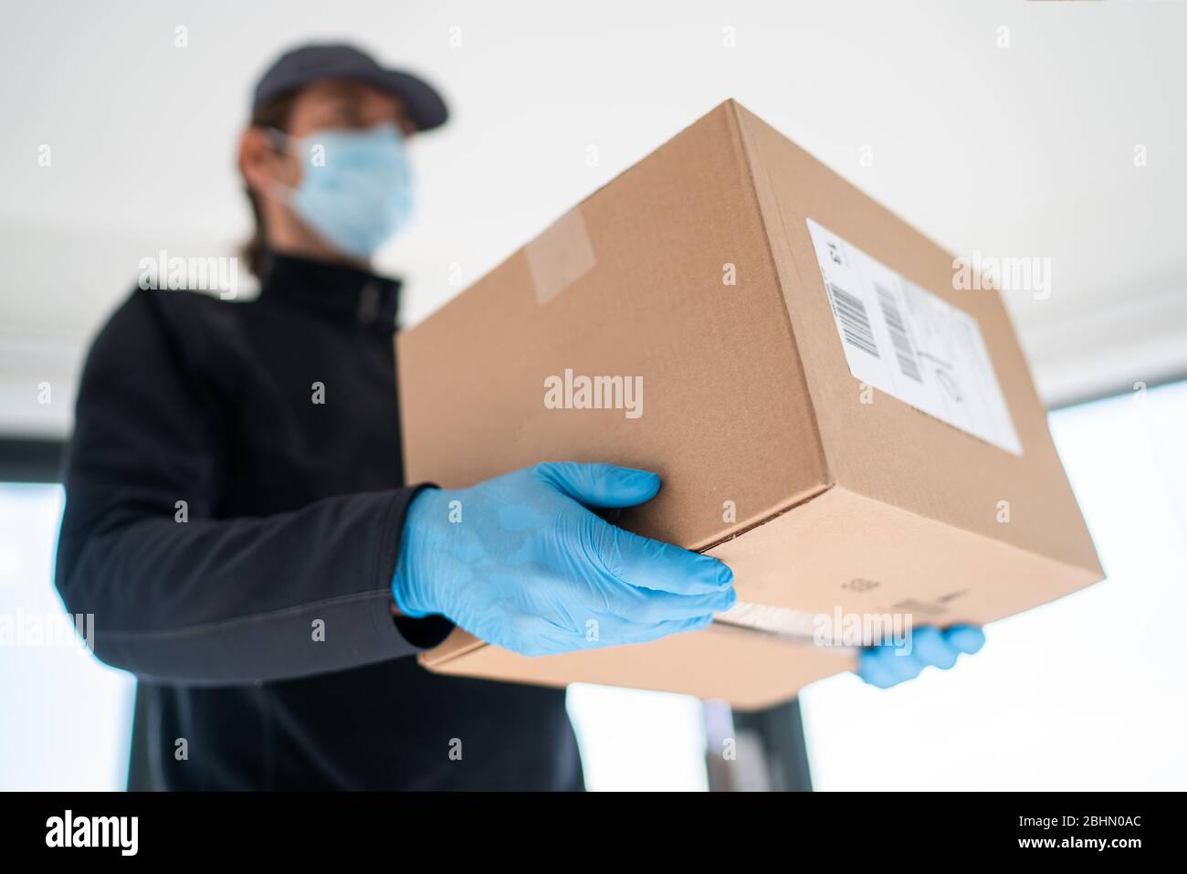 Home Delivery Shopping box Mann trägt Handschuhe und Schutzmaske Pakete an Tür liefern. Stockfoto