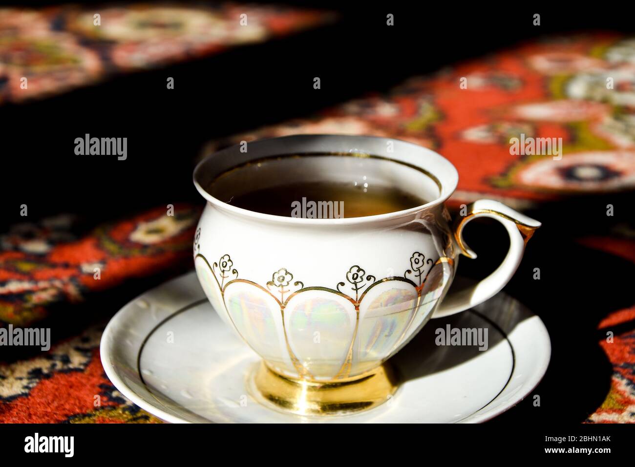 Vintage-Porzellan-Teezeit auf türkischem Teppich, schwarzer Tee mit Rauch  in einer chinesischen Tasse und Untertasse auf dem Sonnenlicht, heißer  Dampf Stockfotografie - Alamy