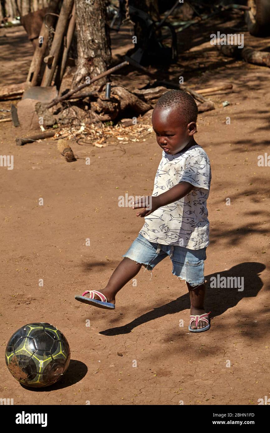 Kleiner afrikanischer Junge, der Fußball spielt, in der Nähe von Matetsi, Simbabwe, Afrika Stockfoto