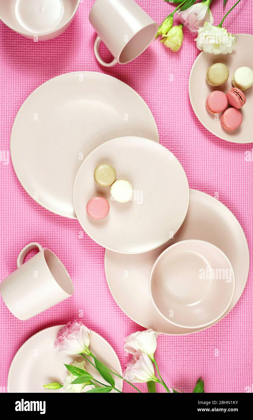 Draufsicht auf modernes, in Pastellrosa gefertigter Keramikgeschirr auf rosafarbenem Boden. Kreatives Konzept Kochen, Küche Flatlay Layout. Vertikal. Stockfoto