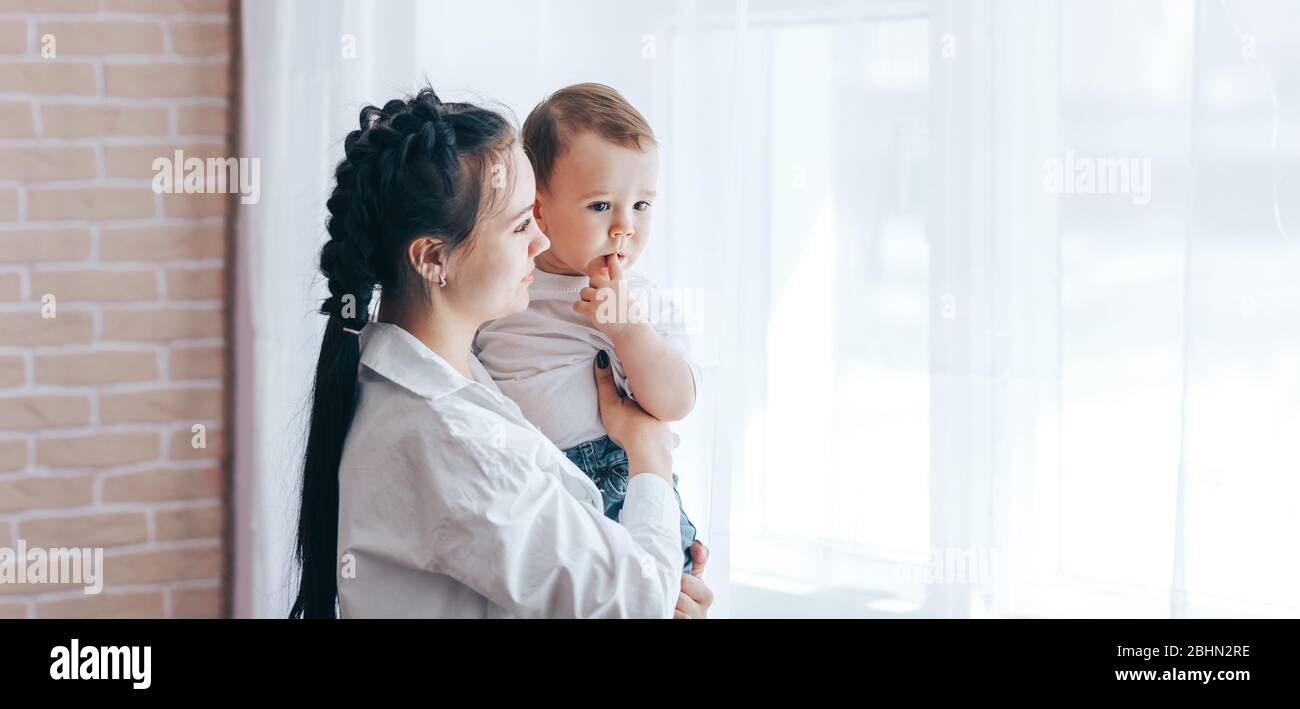Traurige Mutter sitzt mit Baby neben dem Fenster Stockfotografie Alamy