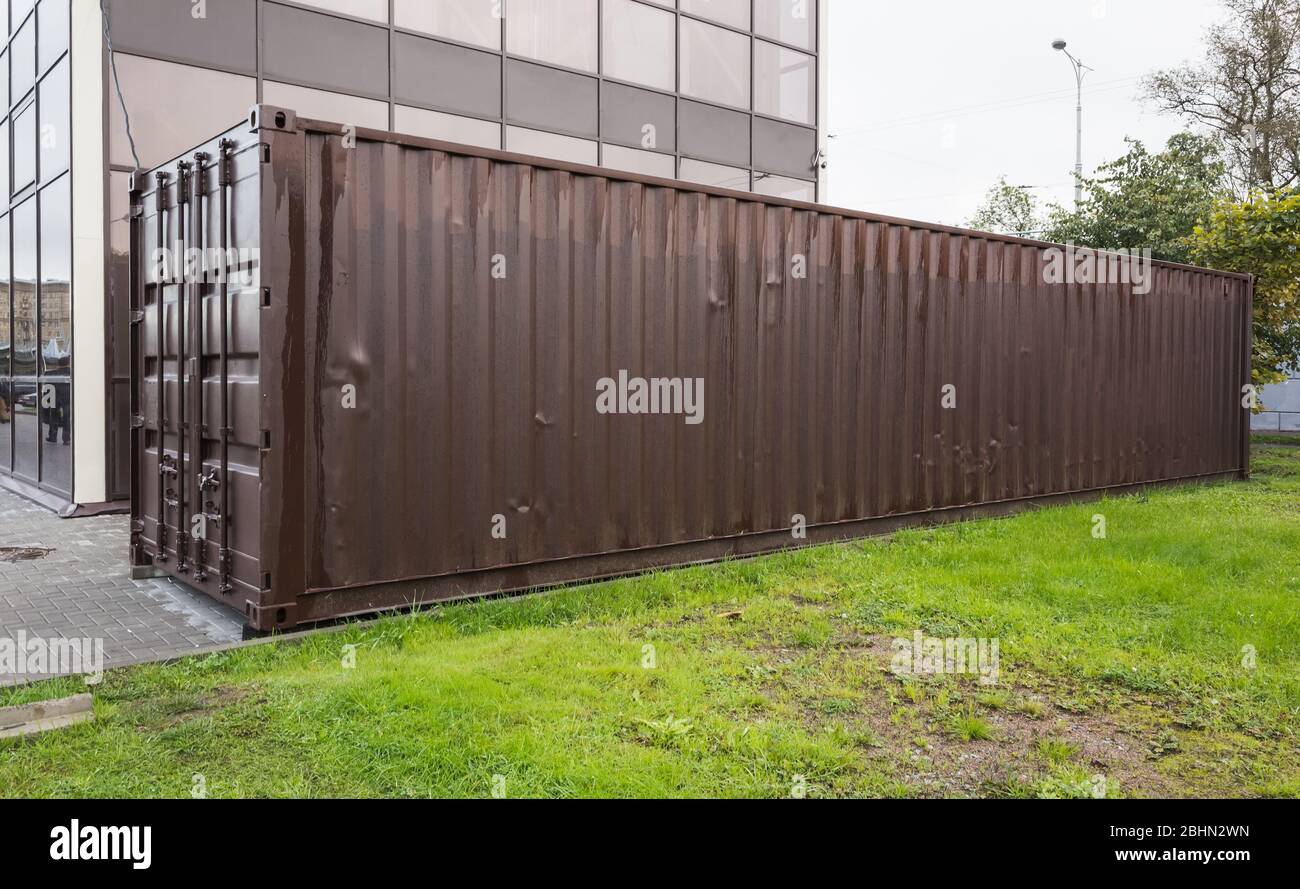 Geschlossene Standard-Fracht-Container steht in der Nähe von grünem Gras, moderne industrielle Schifffahrt Ausrüstung Stockfoto