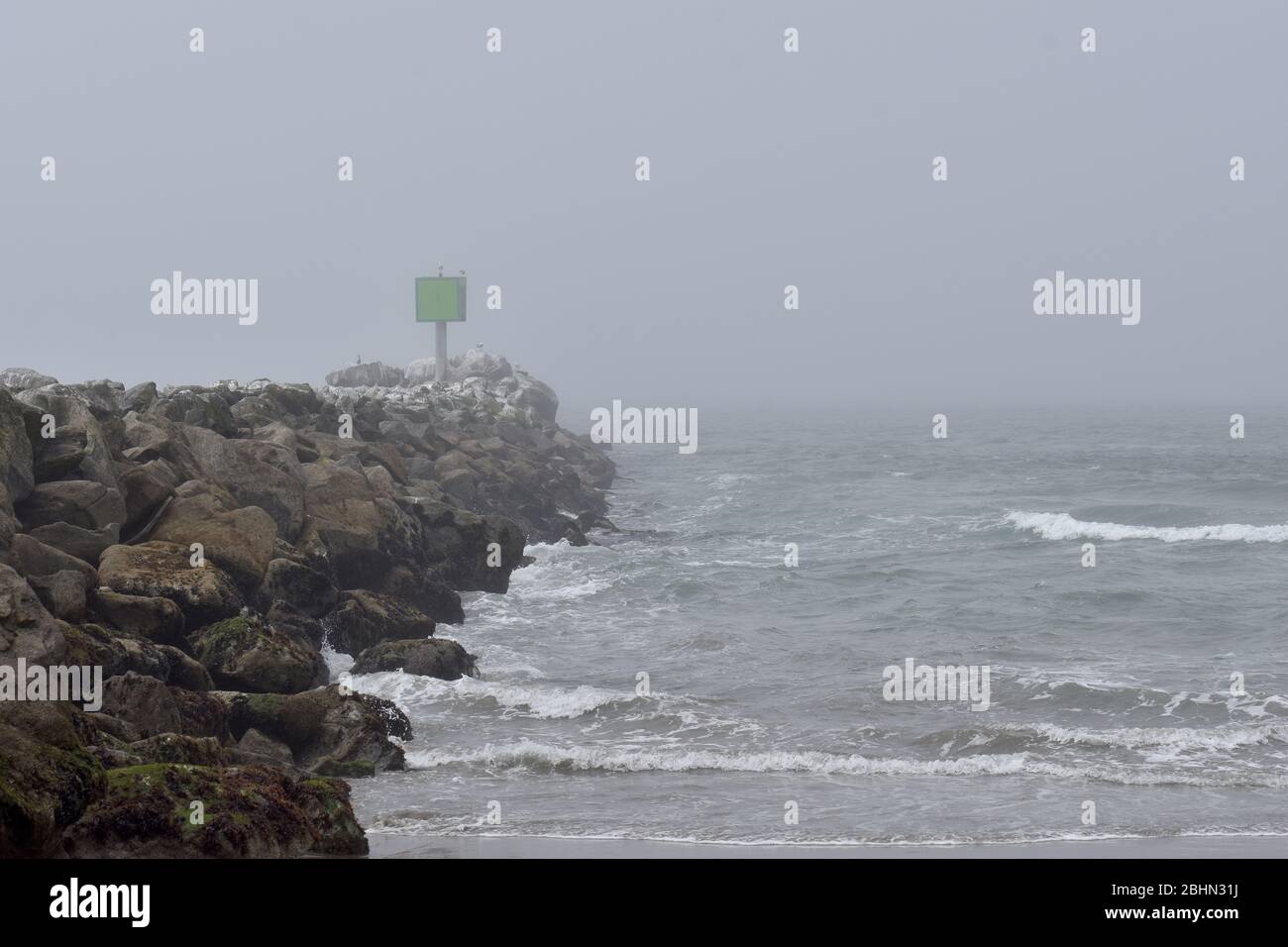 Blick auf das Meer entlang der Wellenbrecher an einem grauen, stürmischen Morgen am Moss Landing State Beach in Kalifornien Stockfoto