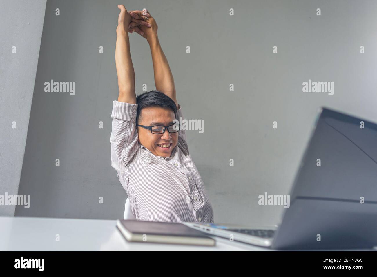 Junger Mann streckt sich den Rücken am Schreibtisch im Büro Stockfoto