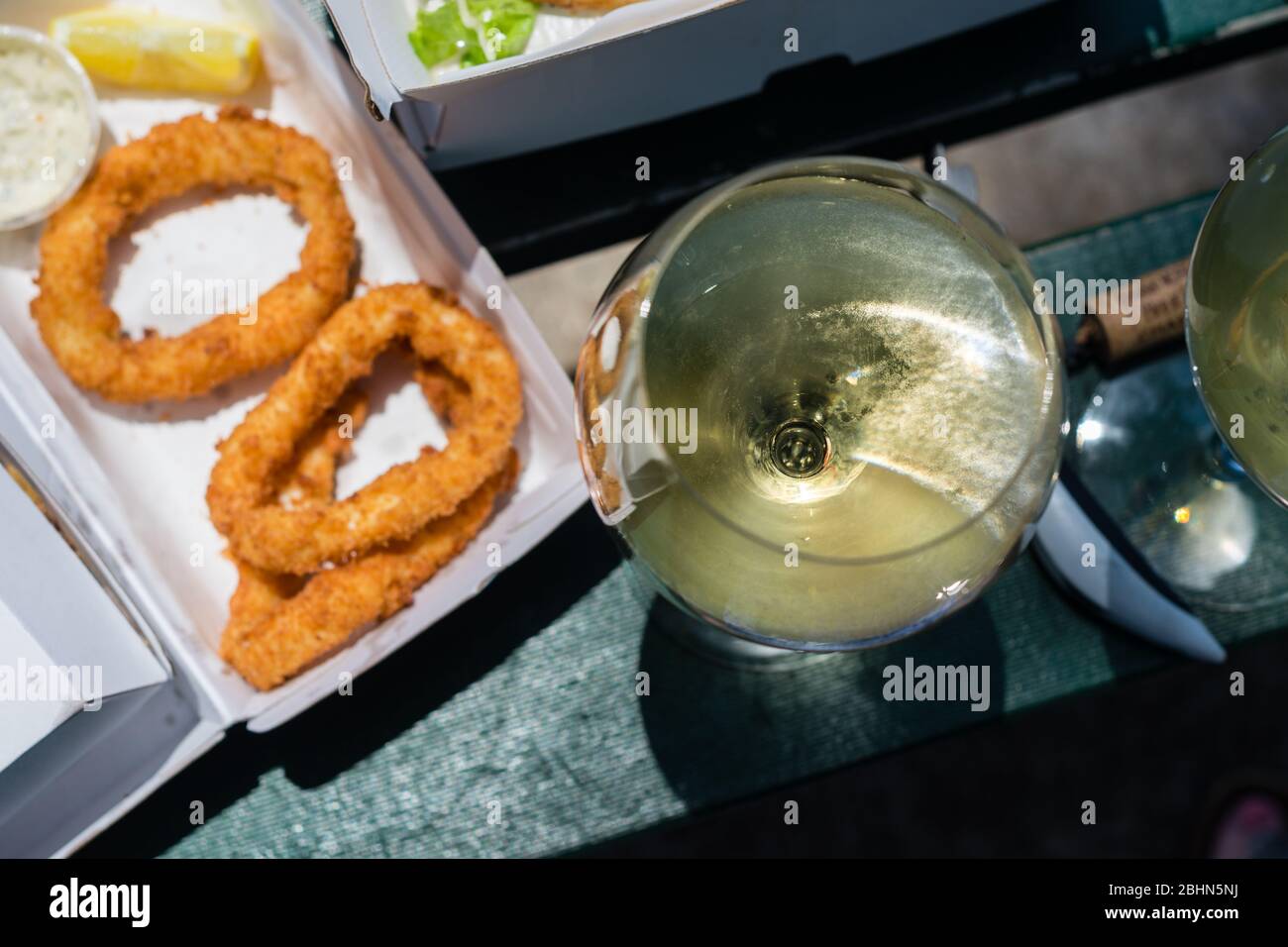 Mittagessen zum Mitnehmen, Fisch und Chips mit einer Flasche Wein, genossen in der Sonne Stockfoto