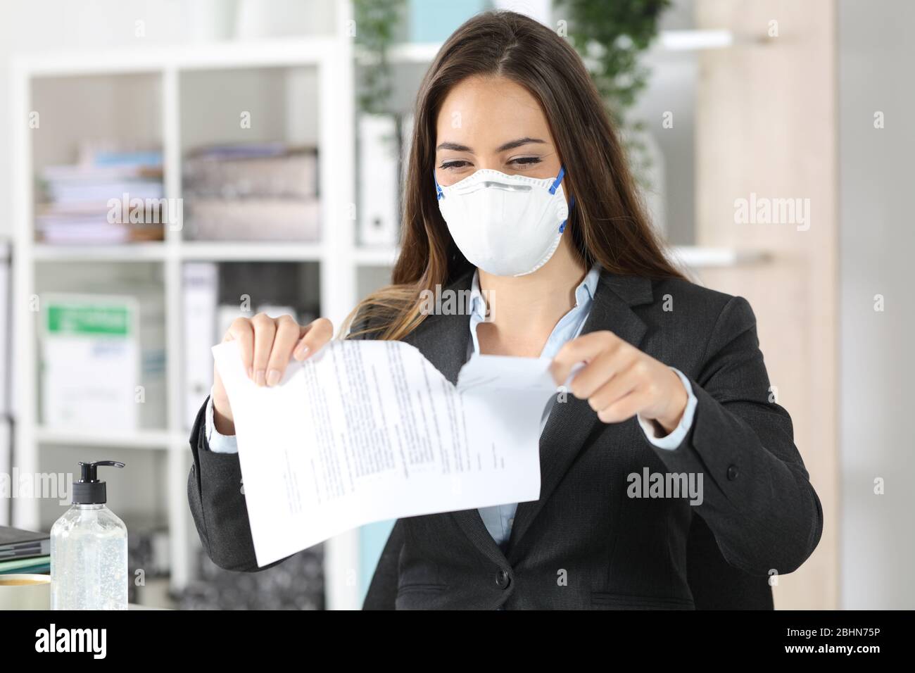 Exekutive Frau trägt Schutzmaske Reifvertrag auf einem Schreibtisch im Büro Stockfoto
