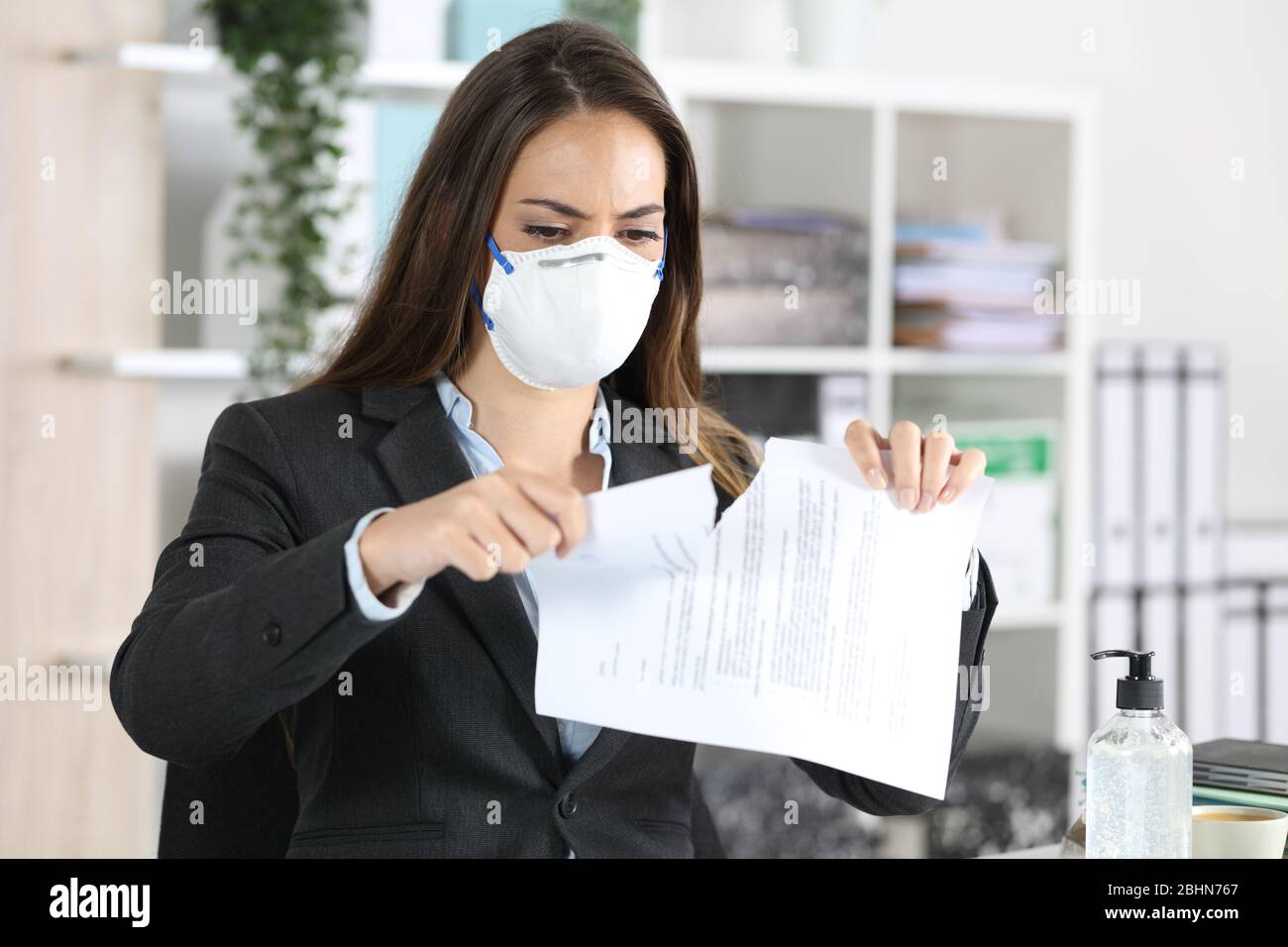 Executive Frau mit Schutzmaske brechen Vertrag auf einem Schreibtisch im Büro Stockfoto