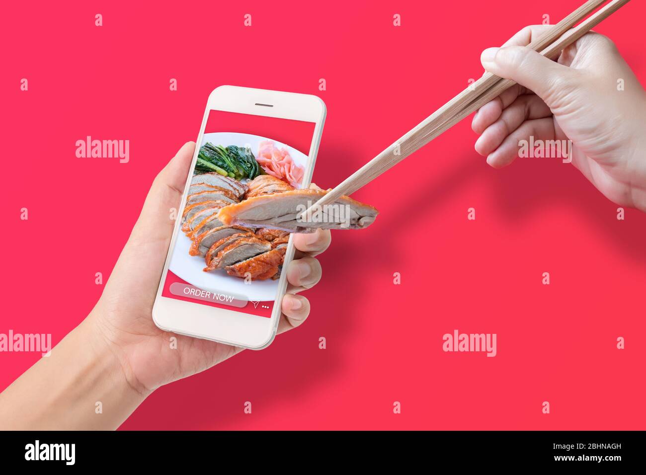 Hand mit Essstäbchen, um die geröstete Ente von der Anwendung zu machen, um Lebensmittel online über mobiles Smartphone, isoliert auf rotem Hintergrund. Stockfoto