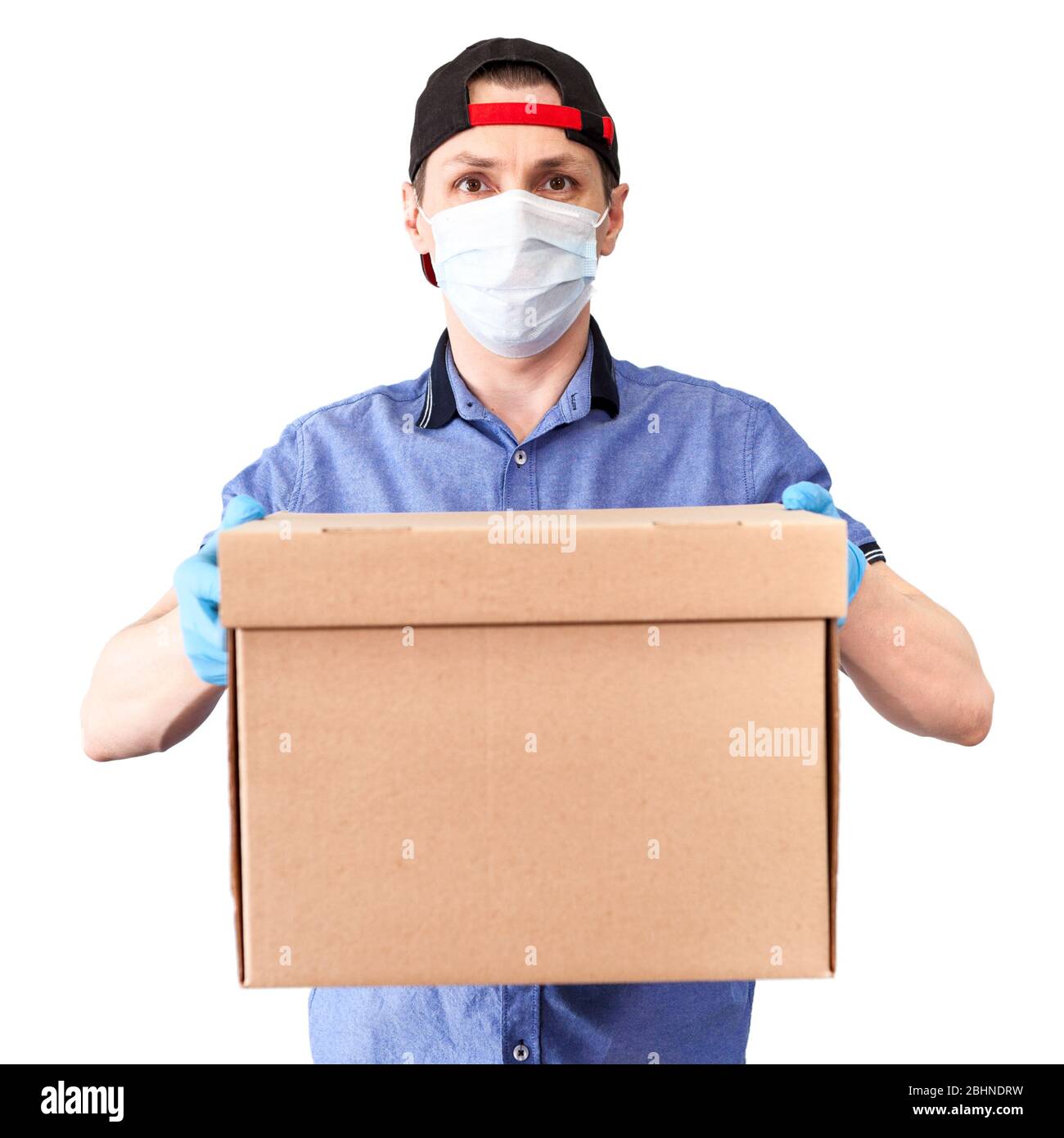 Kaukasische Lieferung Mann trägt medizinische Maske und blaue chirurgische Handschuhe bringt Karton, isoliert auf weißem Hintergrund Stockfoto