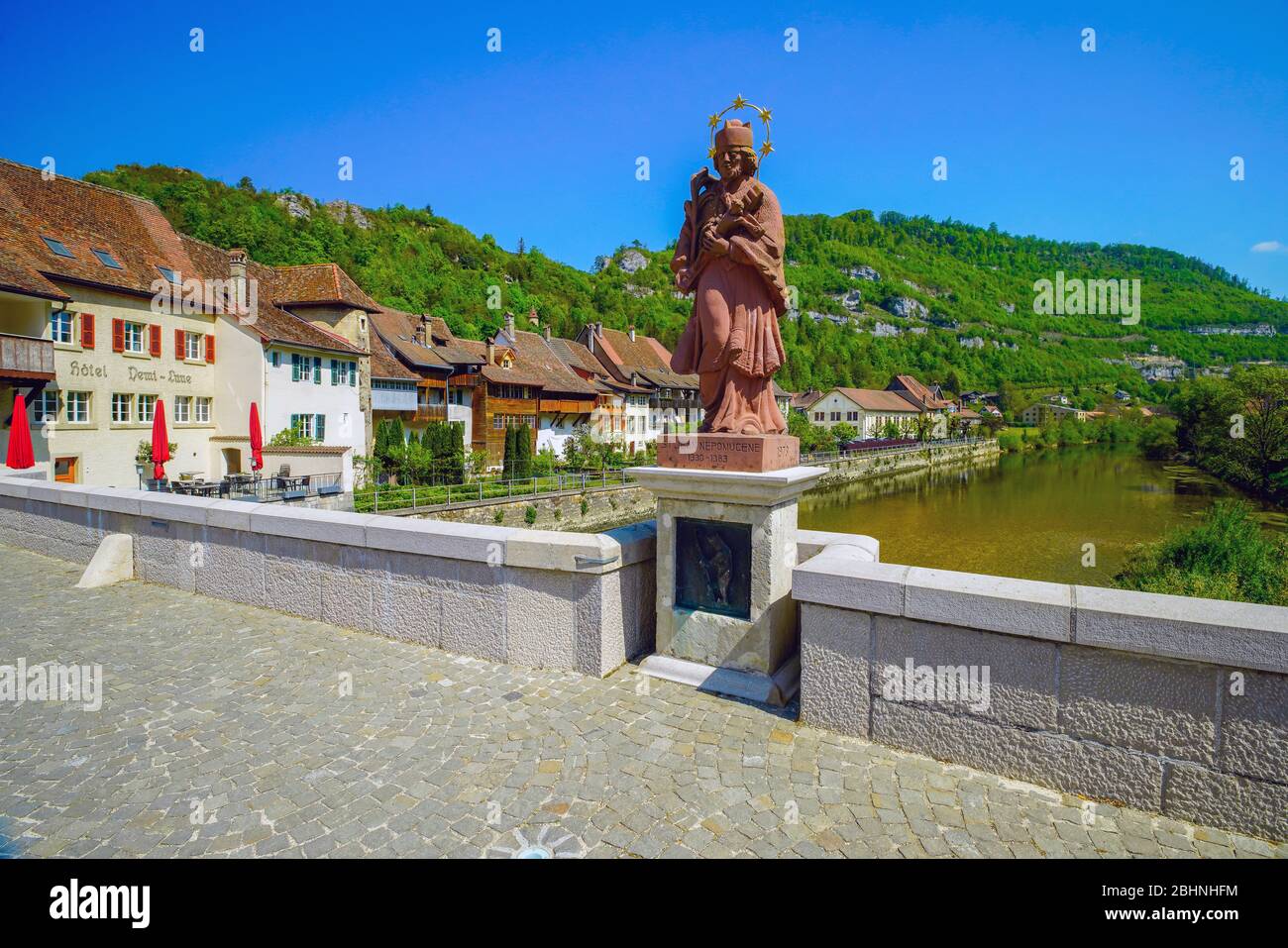 Die Statue Johannes von Nepomuk steht auf halbem Weg auf der Brücke über den Fluss Doubs, Saint Ursanne. Kanton Jura, Schweiz. Stockfoto