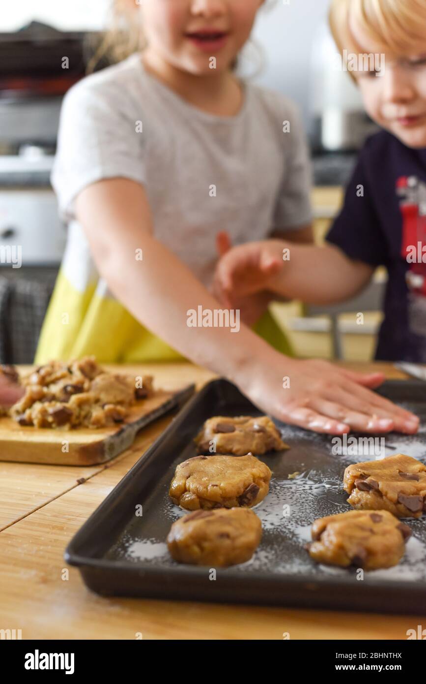 Kinder machen Kekse in der Küche, indem sie Teig auf ein Tablett zum Kochen zu Hause legen Stockfoto