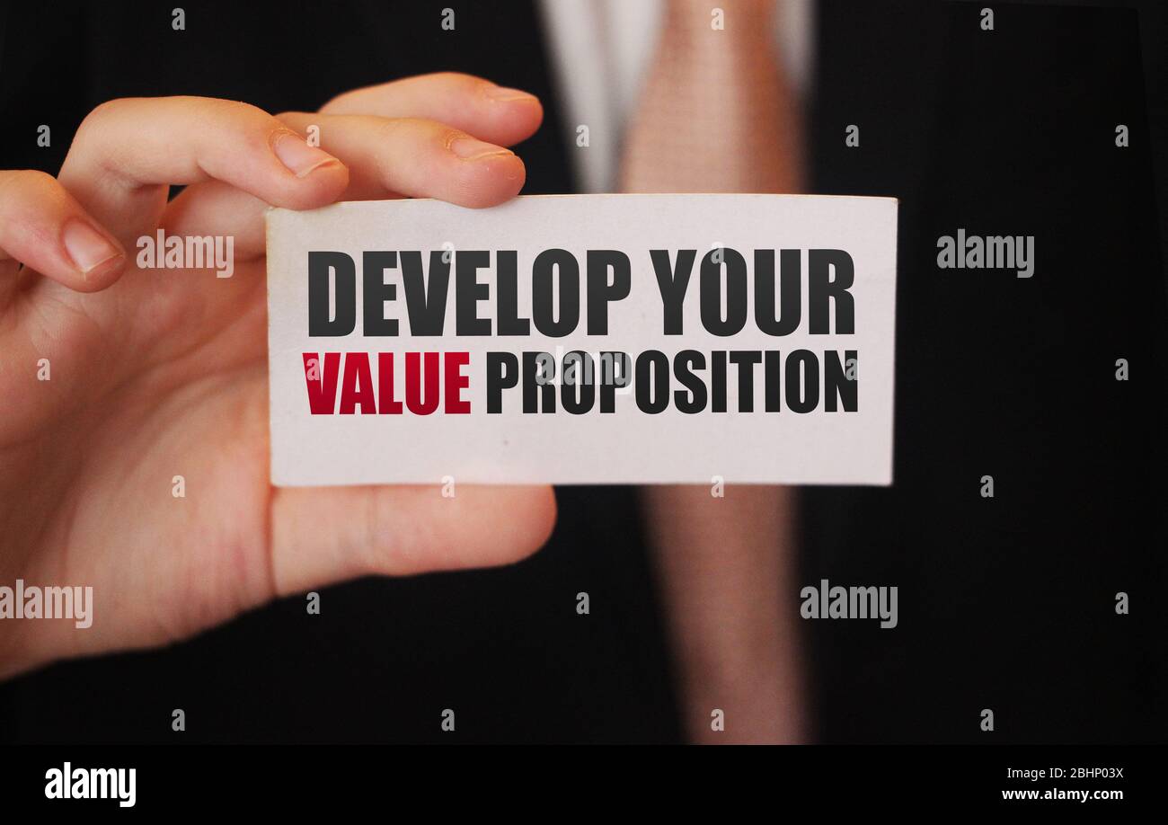 Geschäftsmann zeigt eine Karte mit Text ENTWICKELN SIE IHRE VALUE PROPOSITION. Management Business Leistungen Motivation Konzept Stockfoto