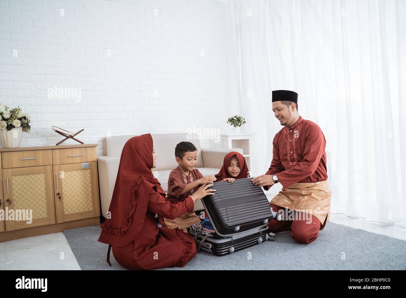Asiatische Familie bereiten Kleidung und legte in einem Koffer, um Mudik in die Heimatstadt gebracht werden Stockfoto Asiatische Familie bereiten Kleidung und legte in einem Koffer, um Mudik in die Heimatstadt gebracht werden Stockfoto