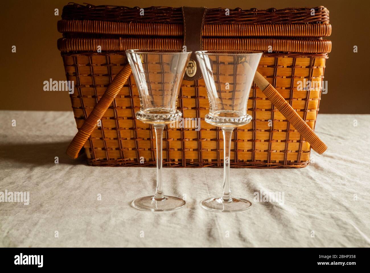 DATE NIGHT: Zwei Weingläser stehen nebeneinander vor einem Picknickkorb auf einem Küchentisch. Stockfoto