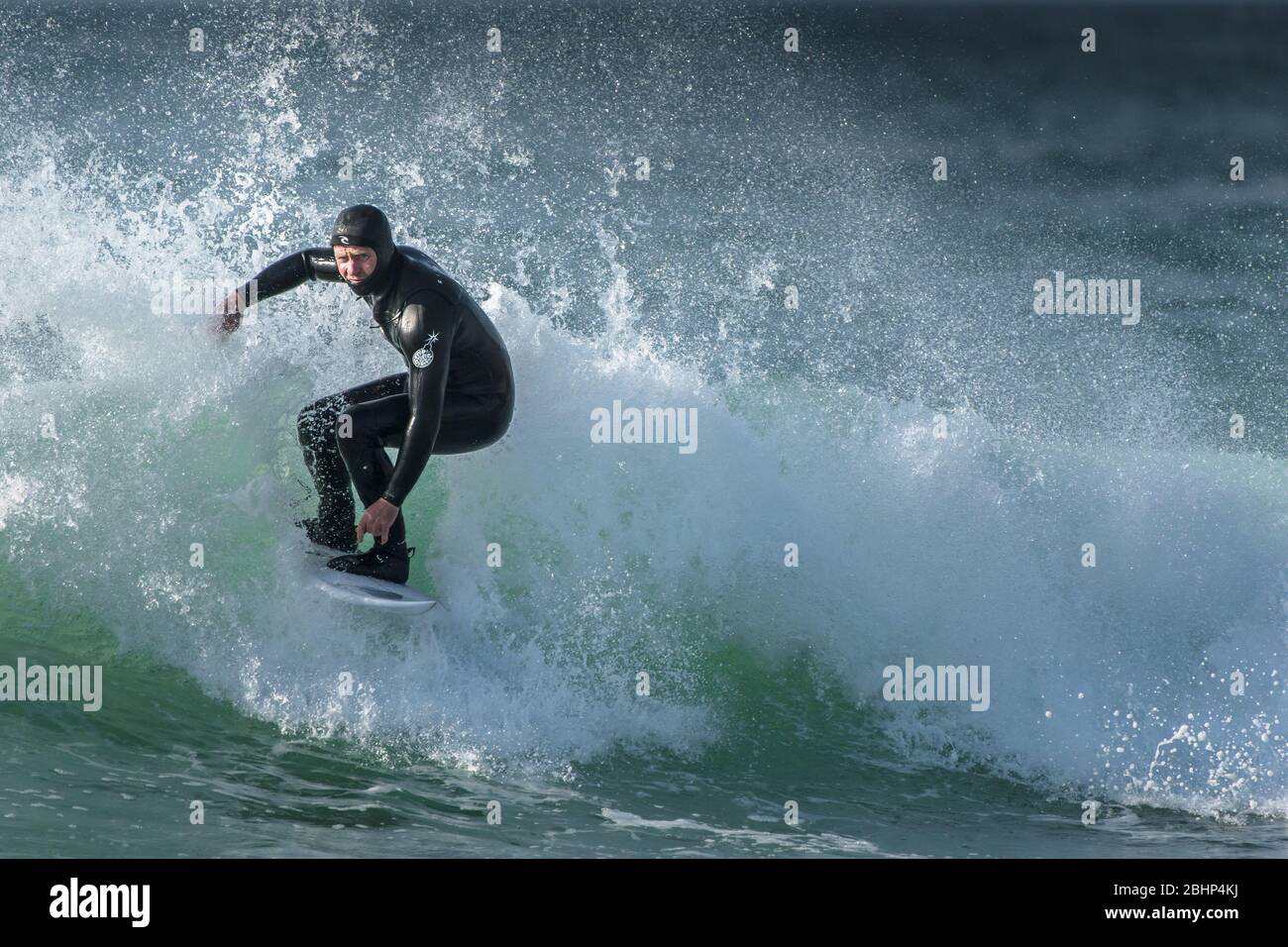 Spektakuläre Surferaction, während ein reifer Surfer eine Welle im Fistral in Newquay in Cornwall reitet. Stockfoto