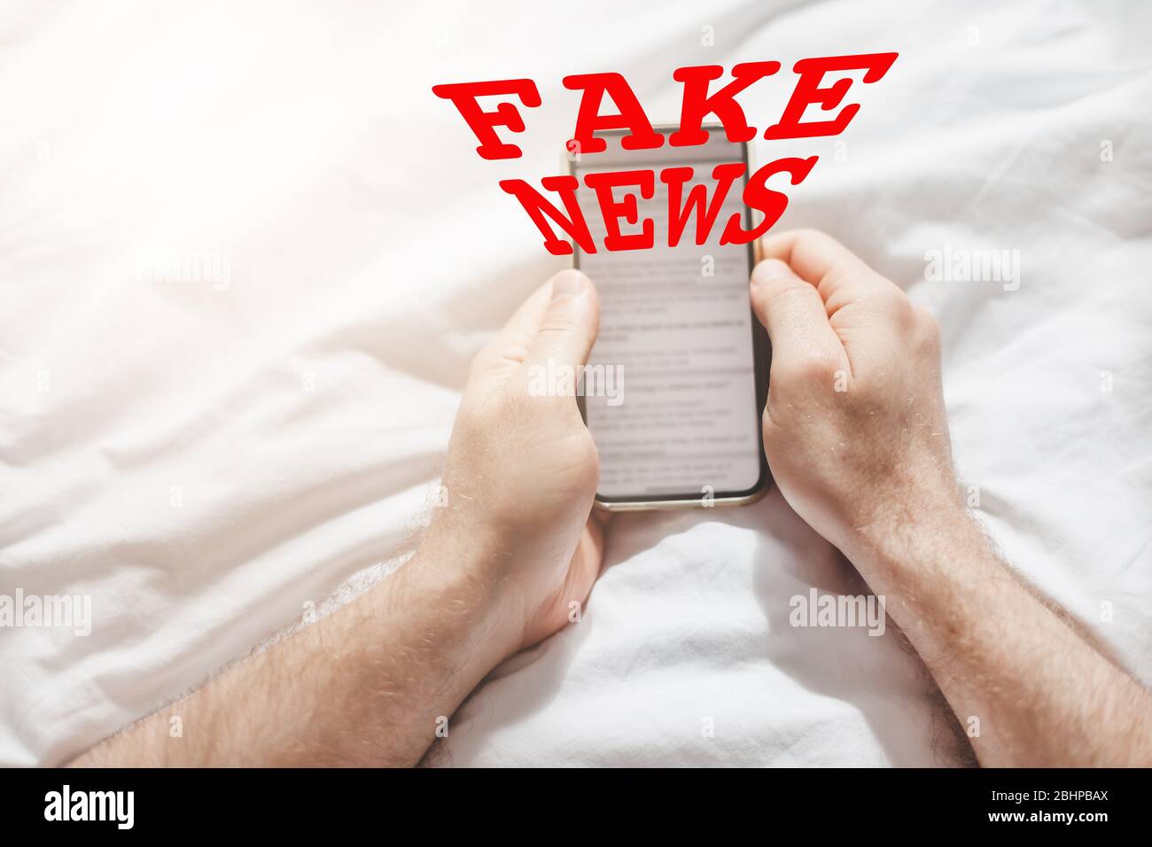 Fake News Infosemics during Covid-19 Pandemie Concept. Mann hält Handy und liest zu Hause Nachrichten oder soziale Netzwerke. Letzte News lesen upd Stockfoto