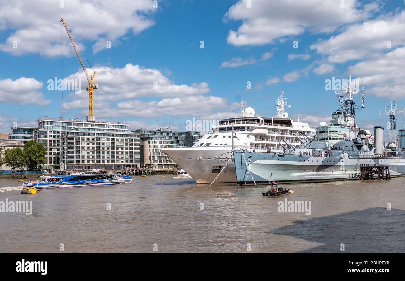 Verkehr auf dem Londoner Fluss. Eine geschäftige Themse mit dem Kreuzfahrtschiff Silver Wind liegt neben der HMS Belfast, während ein Flussbus vorbeifährt. Stockfoto
