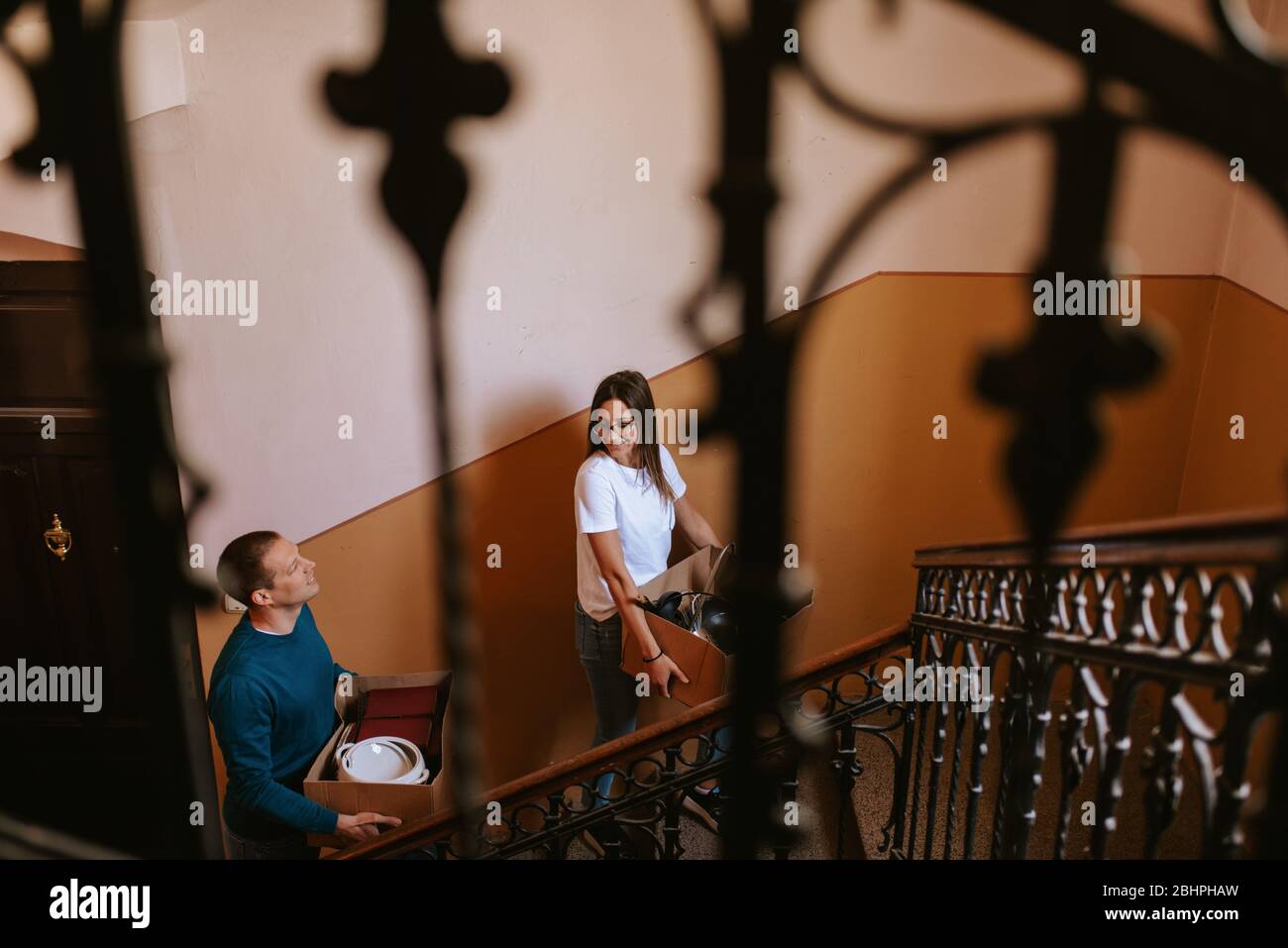 Attraktive kaukasischen Freund und Freundin mit Kisten mit Dingen auf der Treppe im Gebäude. Liebevolles Paar bewegt Stockfoto