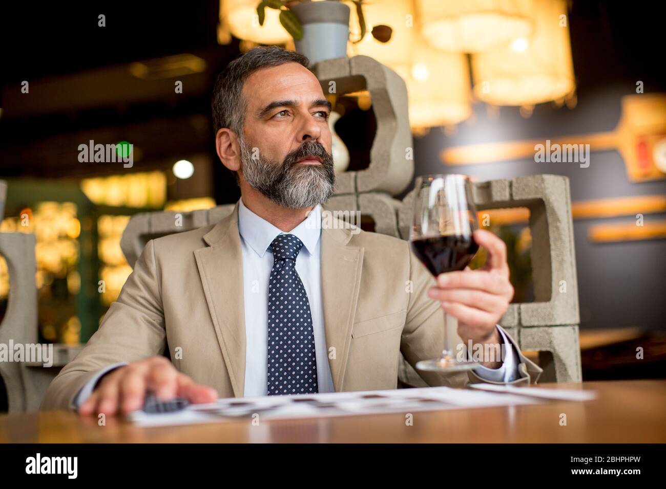 Schöner reifer Mann, der im Restaurant ein Glas Rotwein trinkt Stockfoto