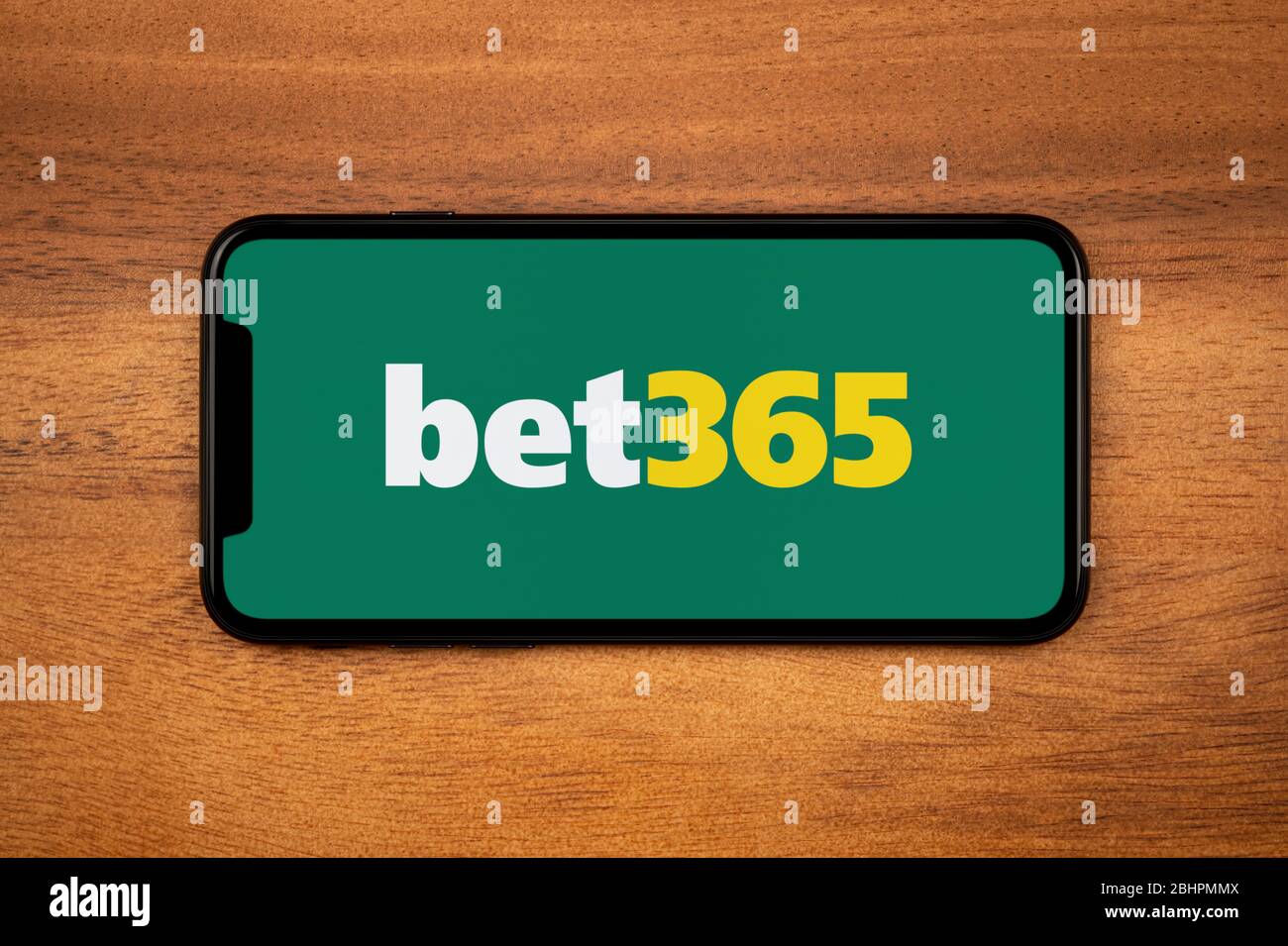 Ein Smartphone mit dem bet365 Logo liegt auf einem einfachen Holztisch (nur redaktionelle Verwendung). Stockfoto