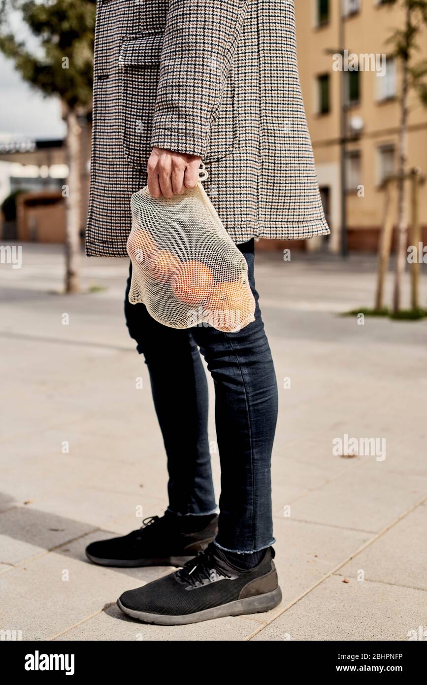 Nahaufnahme eines Mannes auf der Straße mit einem textilen wiederverwendbaren Netzbeutel, verwendet, um Lebensmittel in großen Mengen zu kaufen, voll von Obst und Gemüse, als Maßnahme zu rot Stockfoto