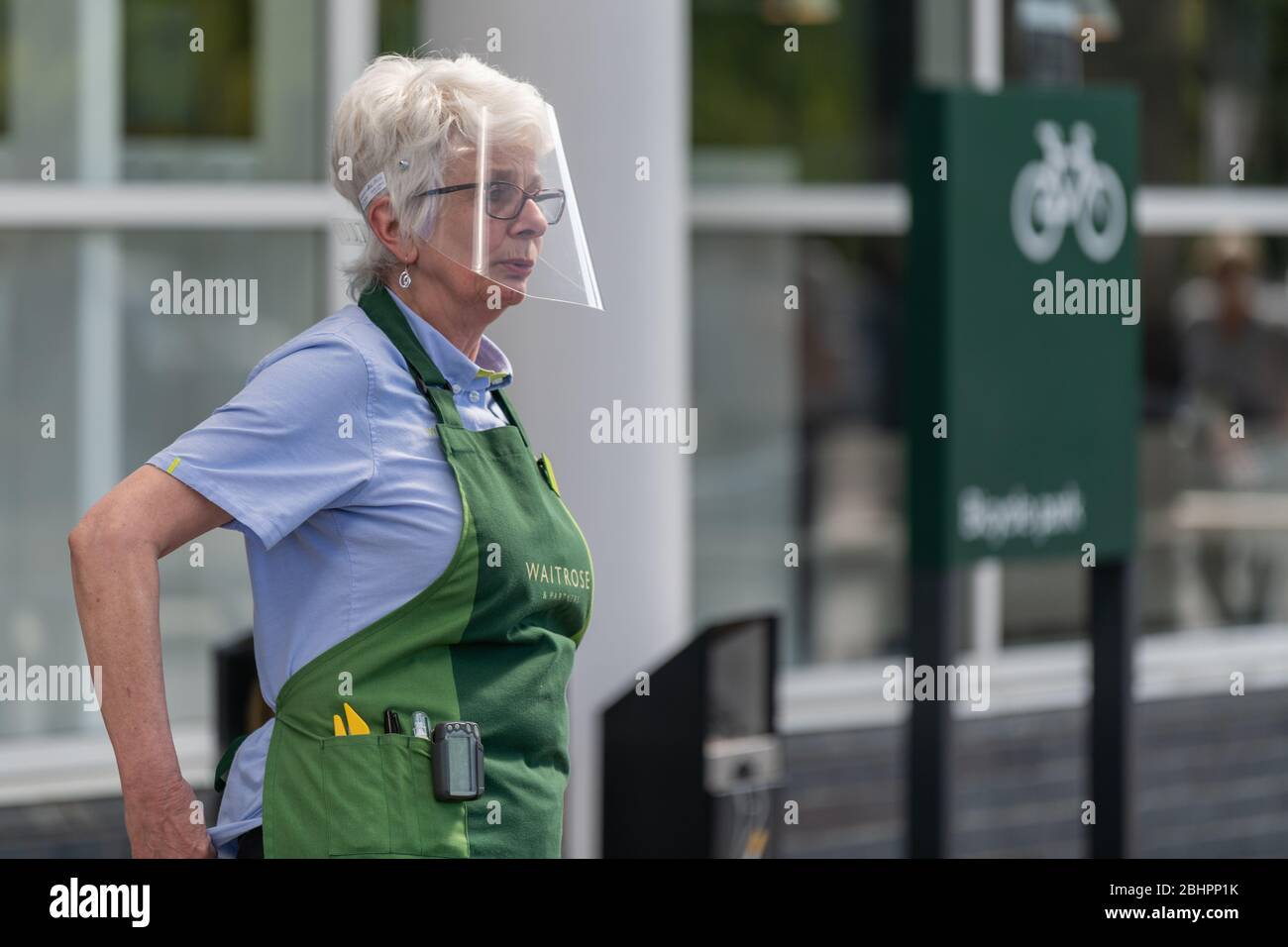 Waitrose & Partners Mitarbeiter trägt einen Gesichtsschutz vor dem Supermarkt Riese. Stockfoto