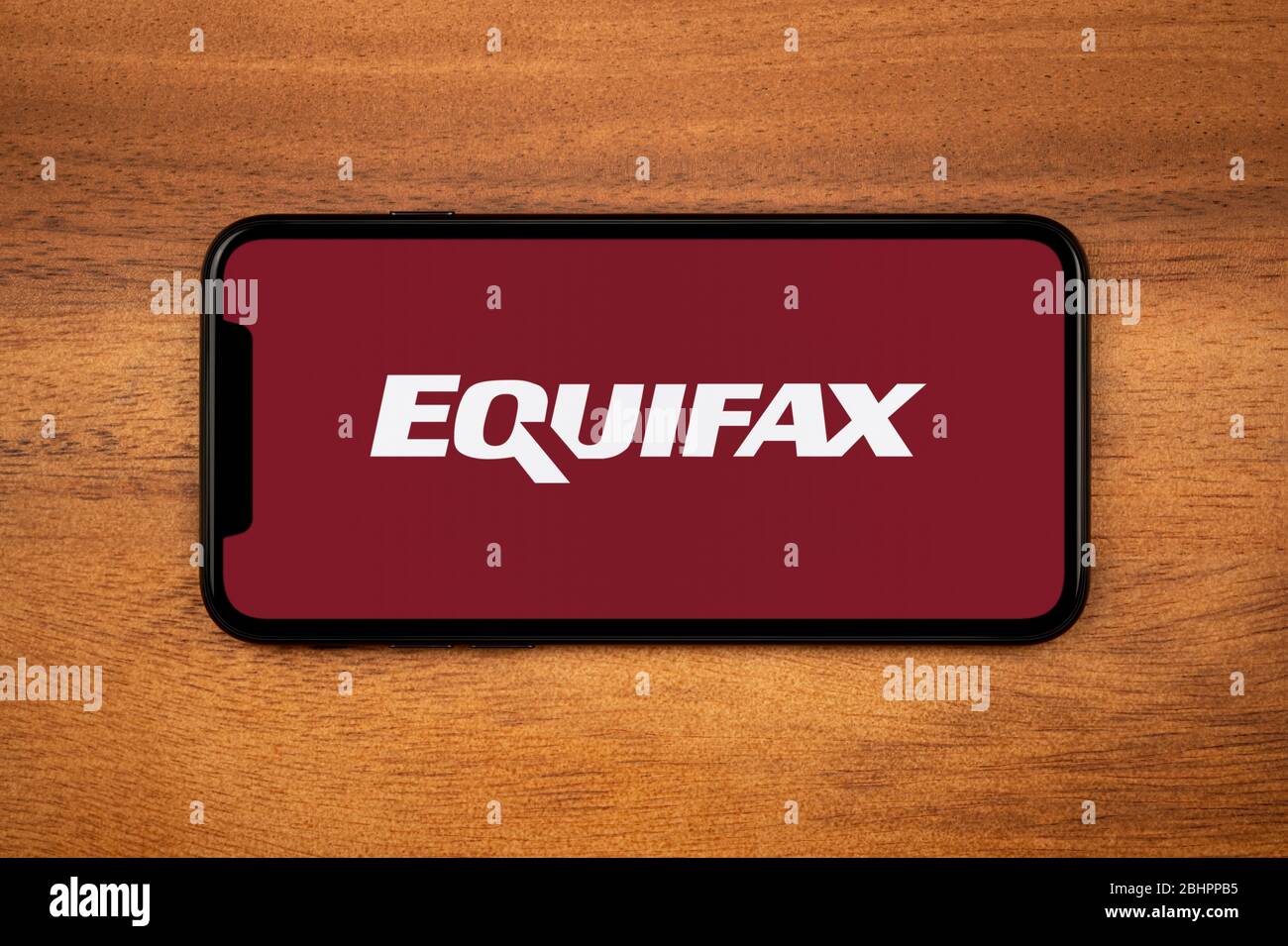 Ein Smartphone mit dem Equifax Logo liegt auf einem einfachen Holztisch (nur für redaktionelle Verwendung). Stockfoto