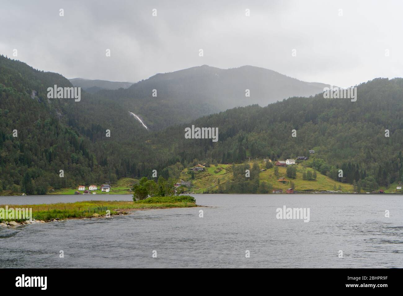 Dörfer Norwegens vor dem Berg: Das Foto wurde im August 2019 während der Mostraumen Fjordkreuzfahrt aufgenommen. Stockfoto