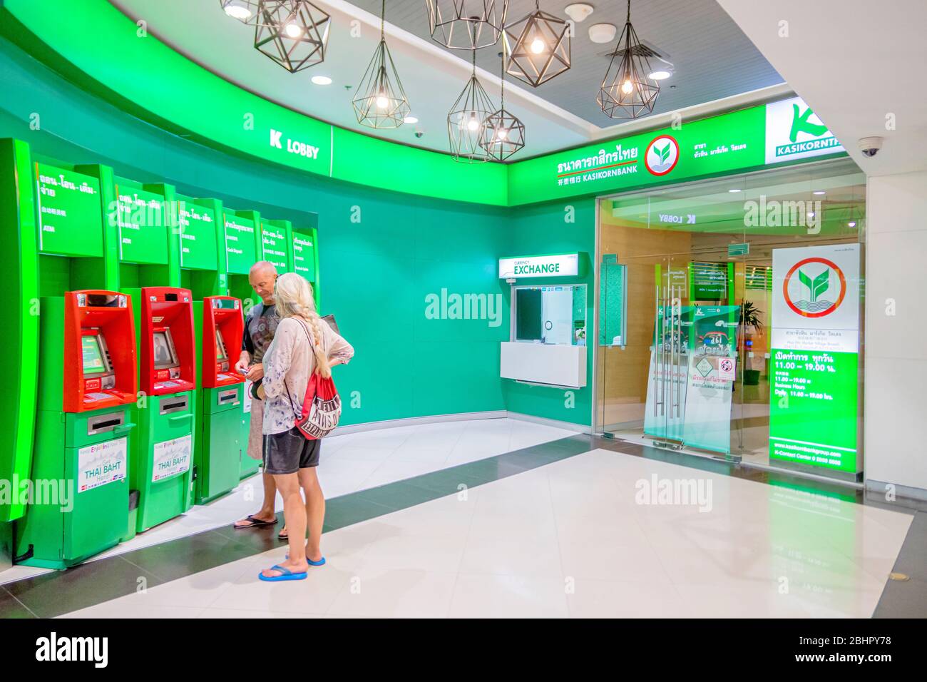 Die Kasikorn Thai Bank im Einkaufszentrum und ihr geldautomat mit zwei ausländischen Kunden, die moner von der Bank in Villagemarket sho abheben Stockfoto