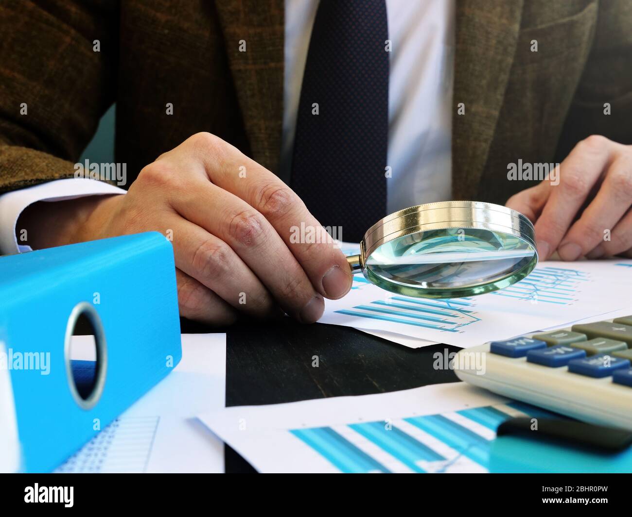 Finanzprüfer macht Prüfung in Unternehmen mit Wirtschaftsbericht und Lupe. Stockfoto
