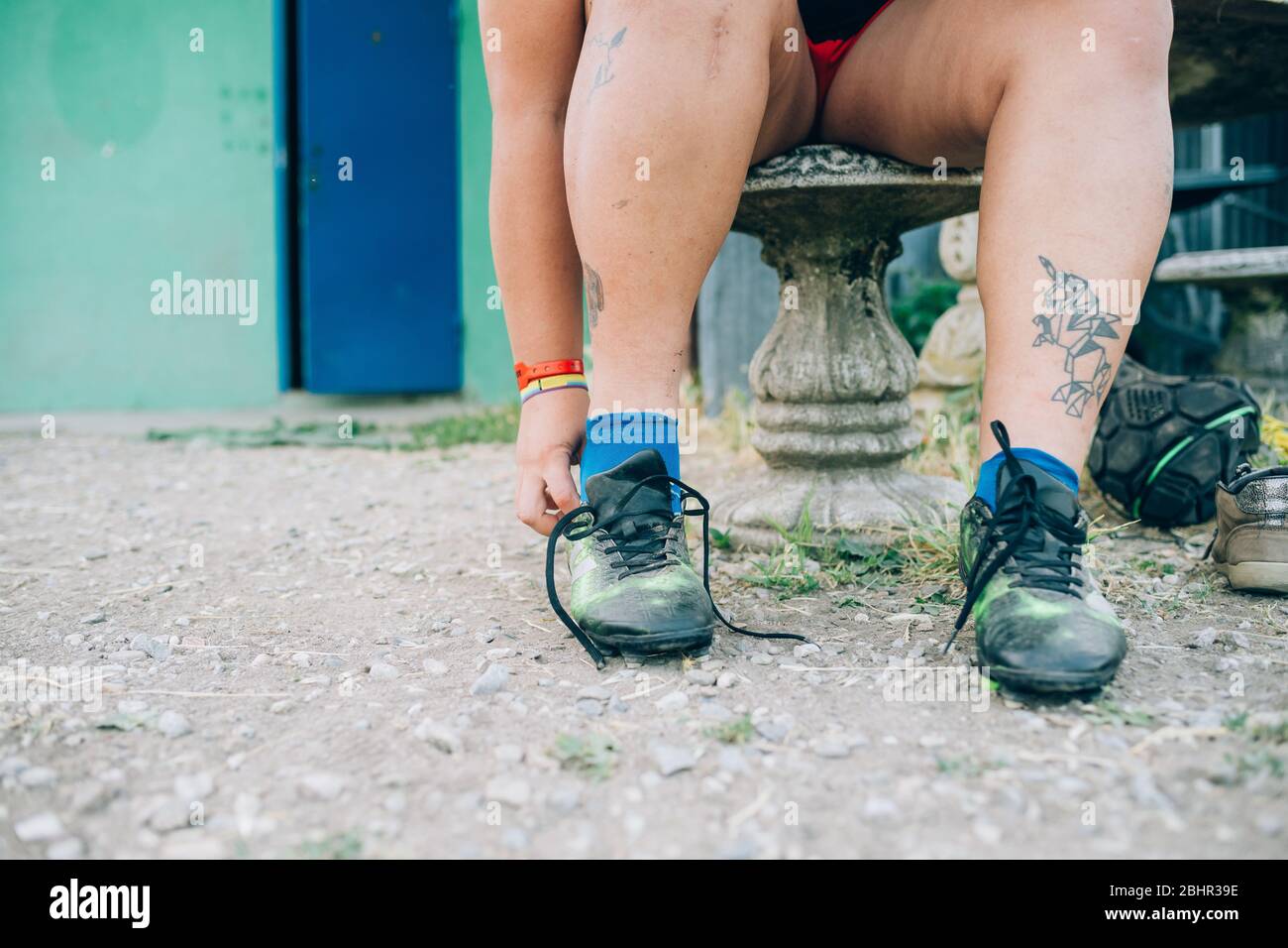 Die Füße und Beine einer Frau, die draußen sitzt und Rugby-Stiefel an. Stockfoto