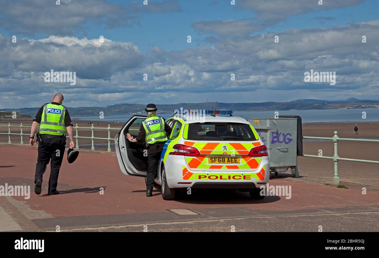 Portobello Beach, Edinburgh, Schottland, Großbritannien. April 2020. Eine Temperatur von 12 Grad mit Sonnenschein und Wolken sehr wenig Wind vor Mittag auf dem sehr ruhigen Strand mit dem gelegentlichen Hundespaziergang und Paare nehmen ihre zulässige Ausübung Zeit, vielleicht reflektieren die letzten 4 Wochen. Polizeiwagen mit zwei Beamten kamen auf der Promenade an und baten kleine Familiengruppen darum, nicht am Strand zu sitzen. Quelle: Arch White/Alamy Live News Stockfoto