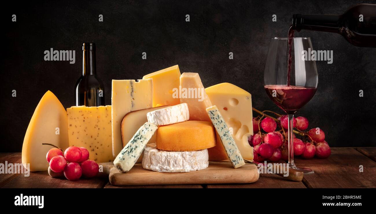 Käsepanorama, verschiedene Käsesorten mit Trauben und Wein, ein Seitenansicht auf dunklem Hintergrund mit einem Platz für Text Stockfoto