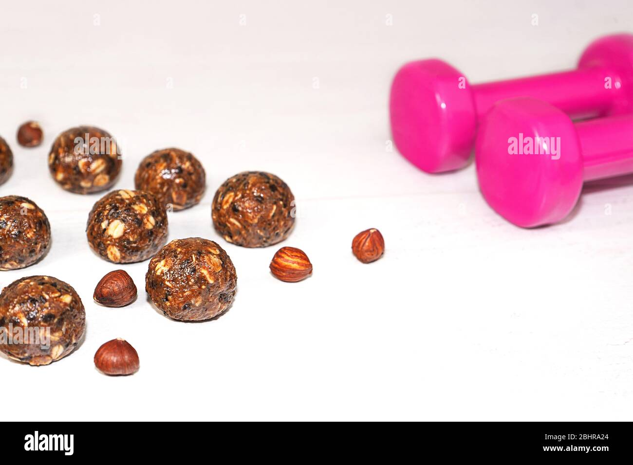 Energiebälle und rosa Hanteln auf Holz Hintergrund. Gesunde Fitness und Rohkost Ernährung. Richtige Ernährung Konzept. Selektiver Fokus. Kopierbereich. Stockfoto