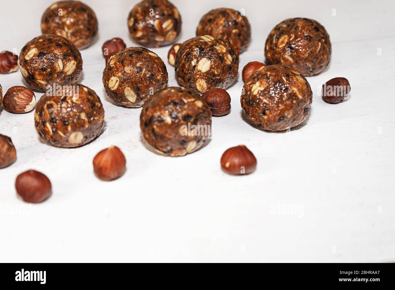 Energiekugeln mit Hafer, Schokolade und Nüssen auf grauem Holzhintergrund. Gesunde vegane und rohe Ernährung. Richtige Ernährung Konzept. Selektiver Fokus. Kopierbereich. Stockfoto