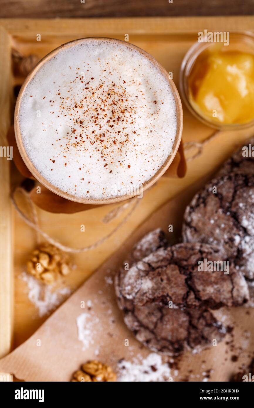 Tasse Kaffee mit aromatischem Schaum und Zimt, Keksen und Marmelade auf rustikalem Hintergrund. Draufsicht. Foto für Werbung oder Banner. Stockfoto