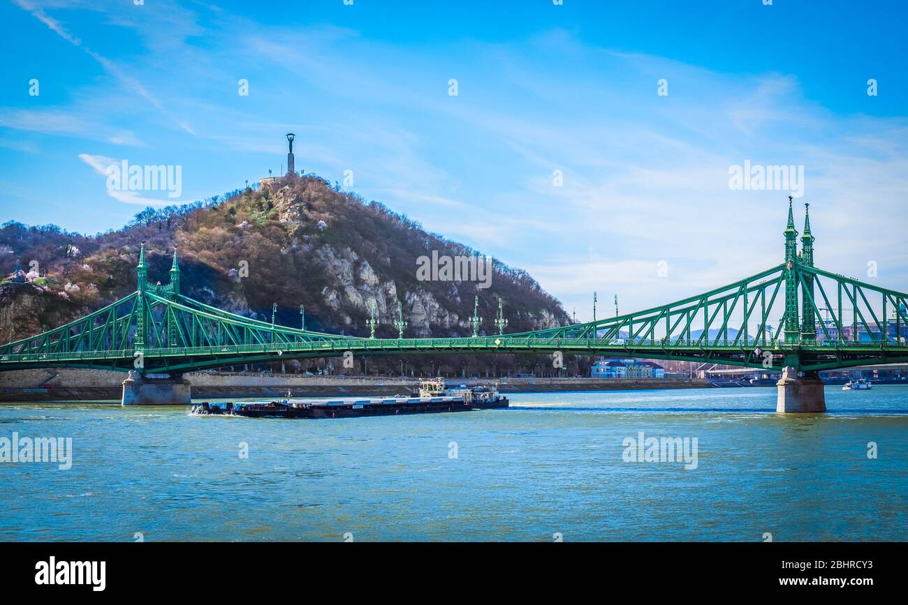 Budapest, Ungarn, März 2020 Blick auf einen Lastkahn, der unter der Freiheitsbrücke über die Donau verläuft Stockfoto