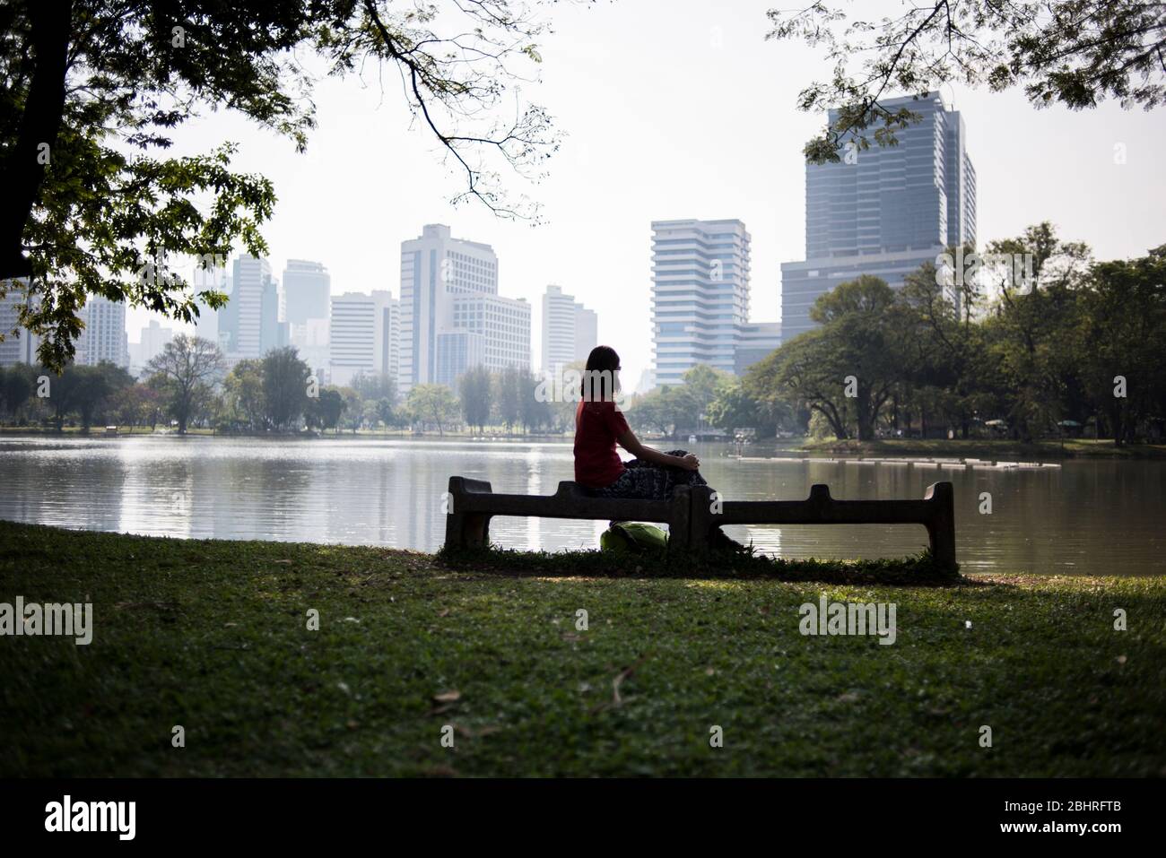 Eine junge Frau ruht in einer Bank im Lumpini Park in Bangkok, Thailand. Stockfoto