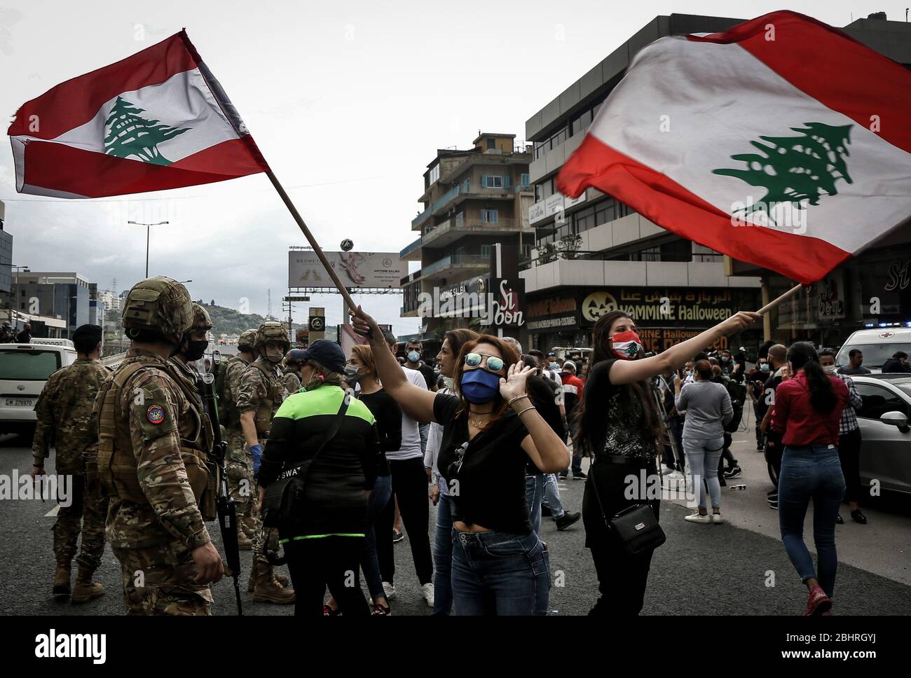 Zouk Mikael, Libanon. April 2020. Regierungsfeindliche Demonstranten schwenken libanesische Flaggen während eines Protestes gegen die hohen Lebenshaltungskosten und die Abwertung der lokalen Währung in Zouk Mikael. Dutzende Demonstranten versammelten sich und blockierten am Montag wichtige Straßen, um gegen die sich verschlechternde Wirtschaftskrise des Landes zu protestieren und sich einer Sperrung des Coronavirus zu widersetzen. Quelle: Marwan Naamani/dpa/Alamy Live News Stockfoto