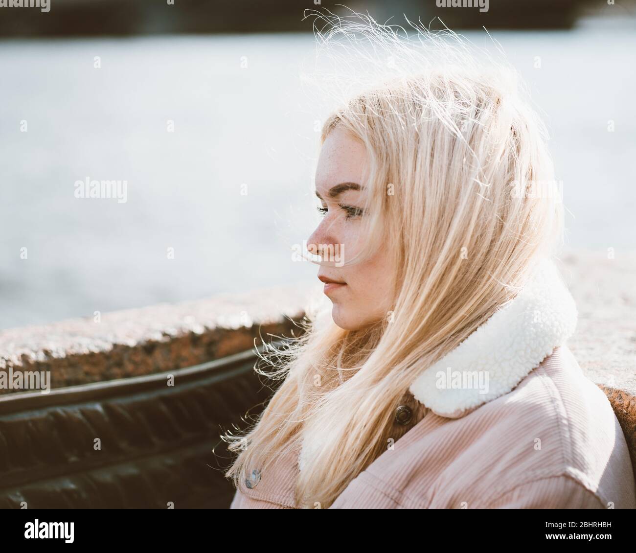 Porträt eines jungen Mädchens, blonde mit gebleichten Haaren, kaukasisch. Skandinavischer Stil. Nahaufnahme einer Teenagerin, die in der Stadt an einer Kamera vorbeischaut Stockfoto