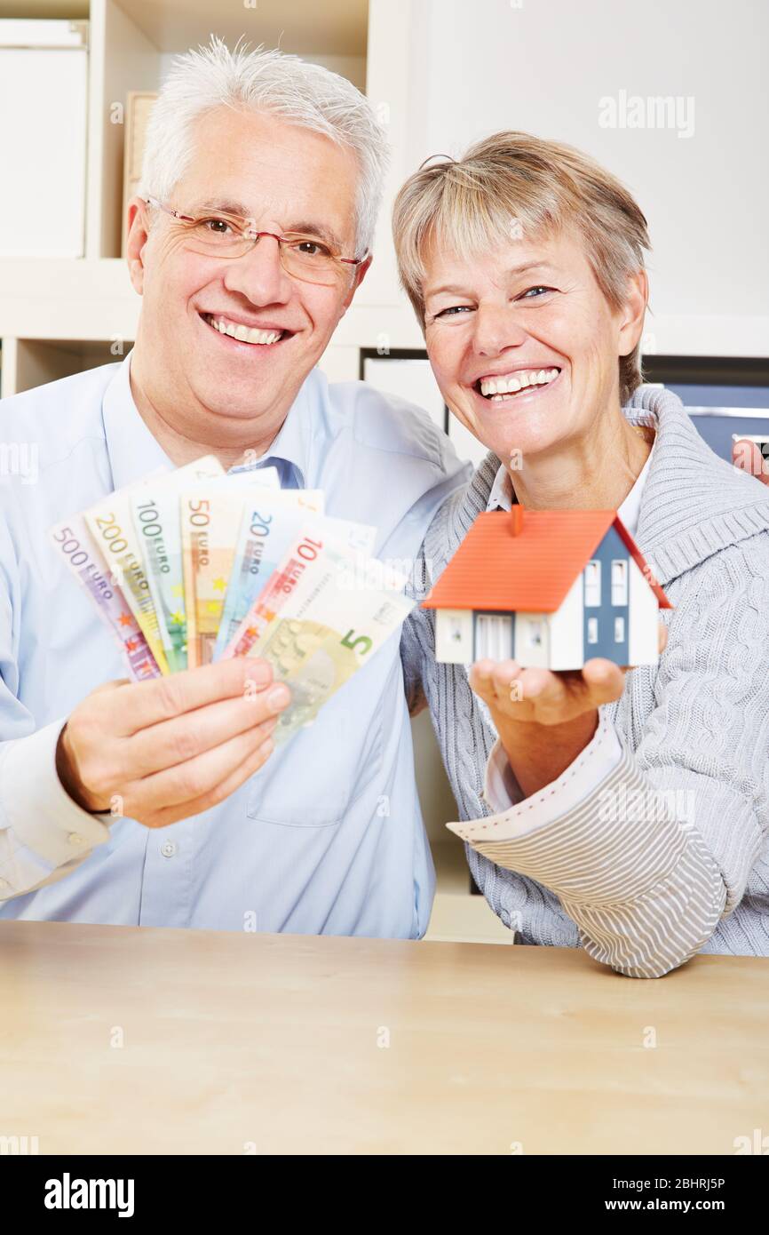 Familie lächelt mit Euro Geld und einem Haus in der Hand Stockfoto