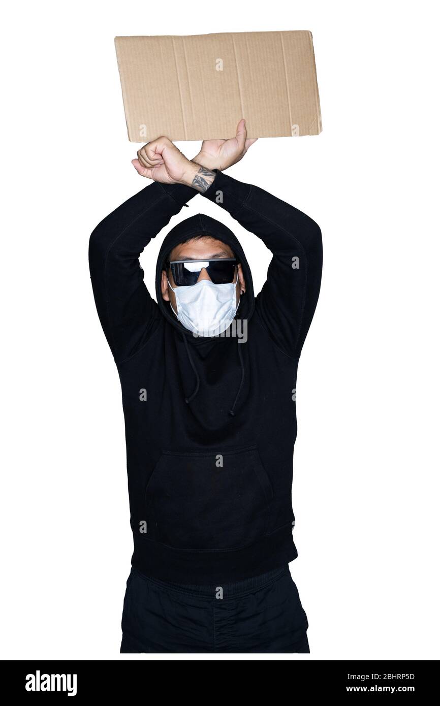 Bärtige asiatische Männer in schwarzen Kapuzenpullover mit medizinischer Maske, die Pappe hält und gekreuzte Arme in weißem Hintergrund zeigt.das Konzept des Protests, atte Stockfoto