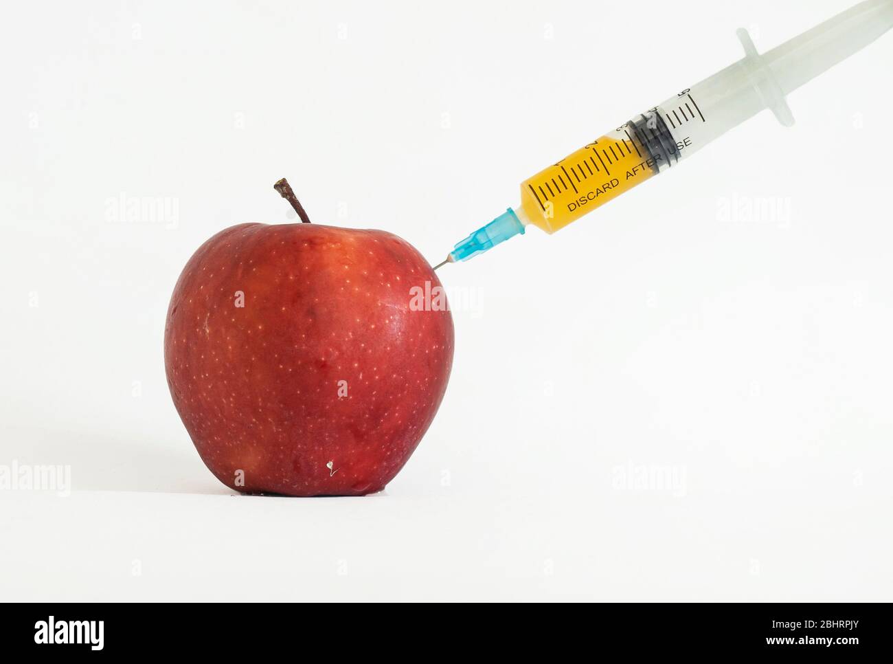 Pestizide und Nitrate werden mit einer Spritze in einen roten Apfel injiziert. GVO-Konzept und genetisch veränderten Organismus. GVO frei und natürliche Früchte mito Stockfoto
