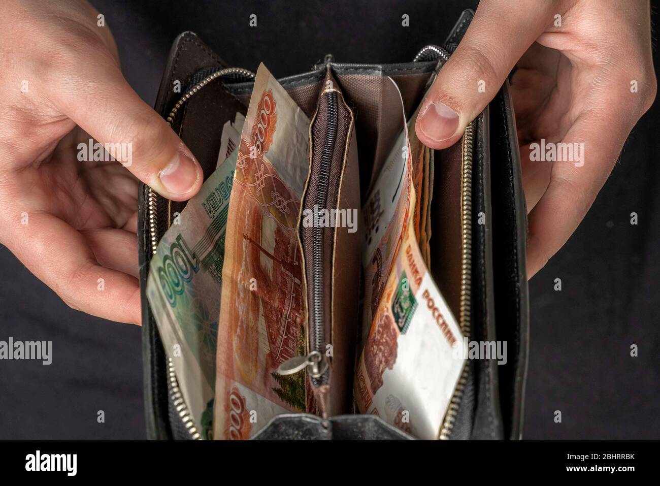 Ein Mann mit einer schwarzen Brieftasche voller russisches Geld. In einer schwarzen Brieftasche, Banknoten sind meist 5,000 Rubel pro Stück. Gehalt und Rente erhöht, Leistungen Stockfoto