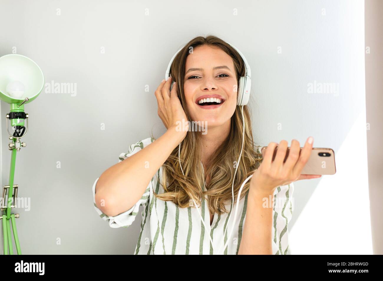 Porträt einer glücklichen Frau mit Headsets Musik hören und lächeln im Haus Stockfoto