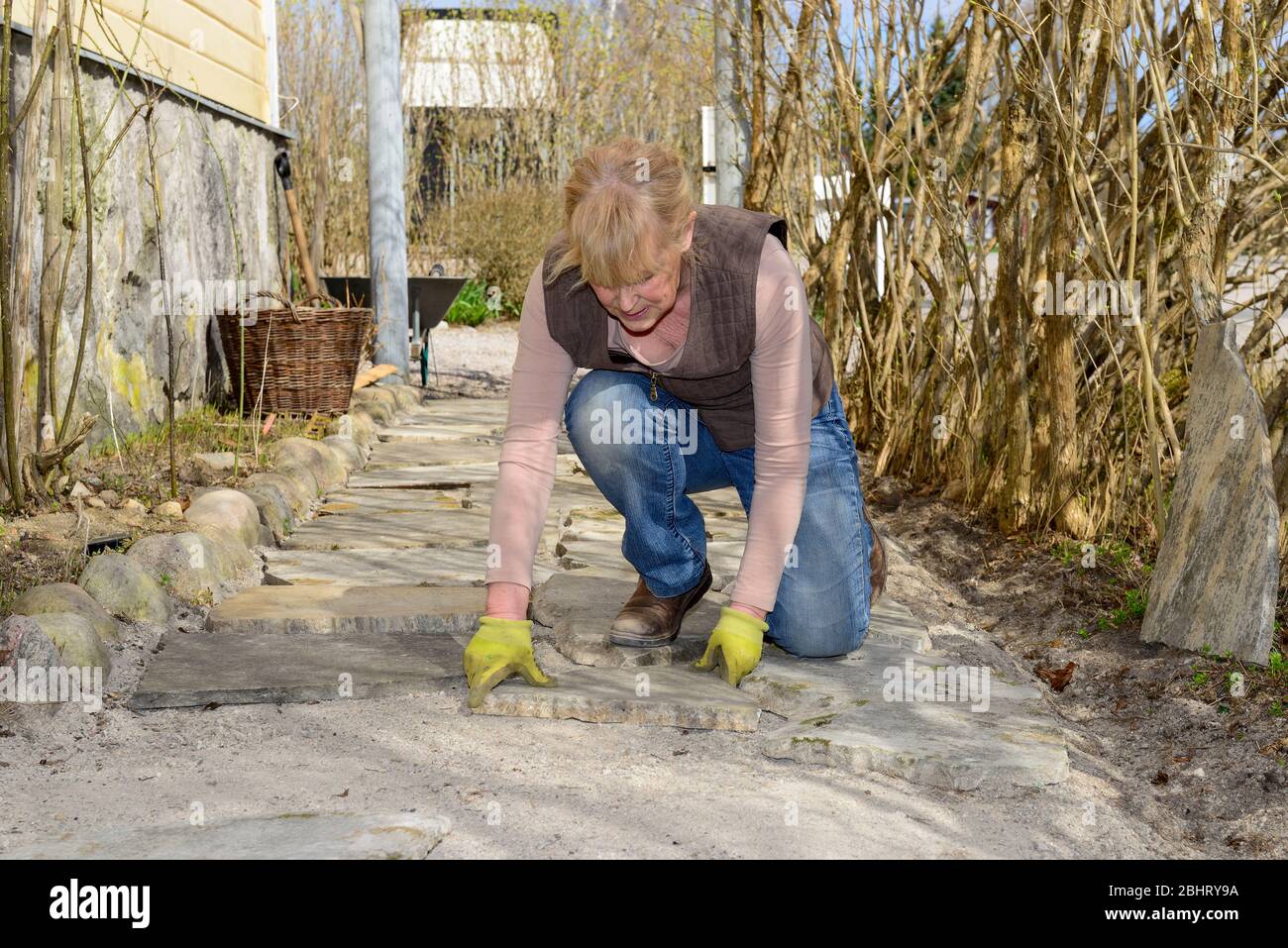 Eine Frau, die mit Steinplatten in einem Hausgarten in Vingåker, Södermanland, Schweden arbeitet Stockfoto
