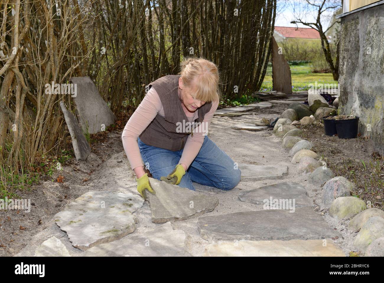 Eine Frau, die mit Steinplatten in einem Hausgarten in Vingåker, Södermanland, Schweden arbeitet Stockfoto