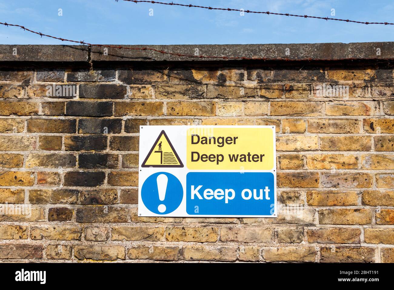 Ein Schild mit der Warnung "Danger Deep Water: Keep Out" an der Grenzmauer eines überdachten unterirdischen Reservoirs in Haringey, London, Großbritannien Stockfoto
