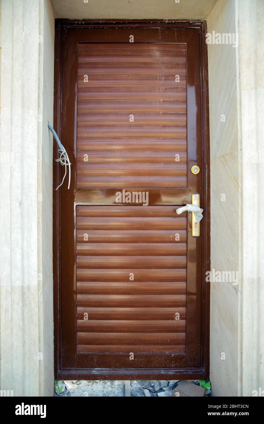 Braune Wand. Goldene Blumen. Mikrofon und Kamera, um die Person an der Tür zu sehen. Tür aus schwarzem Kupfer-Metall. Stockfoto