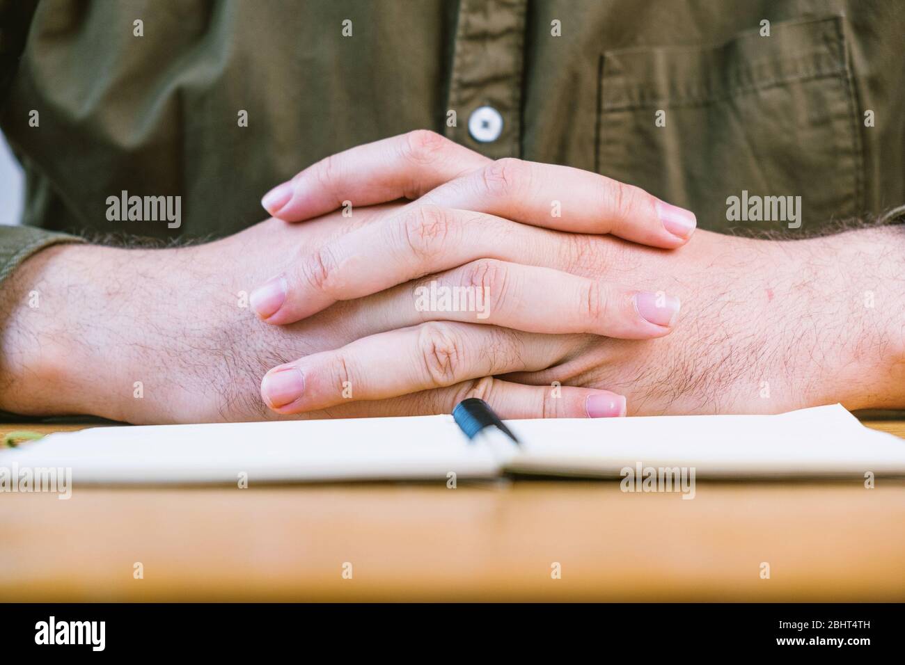 Mann, der die Finger während des Meetings auf dem Schreibtisch hält, konzentriert sich auf die Hände Stockfoto